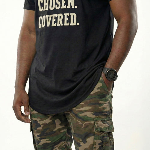 Person wearing a black t-shirt with 'CHosen. COVERED.' text and camouflage pants on a white background