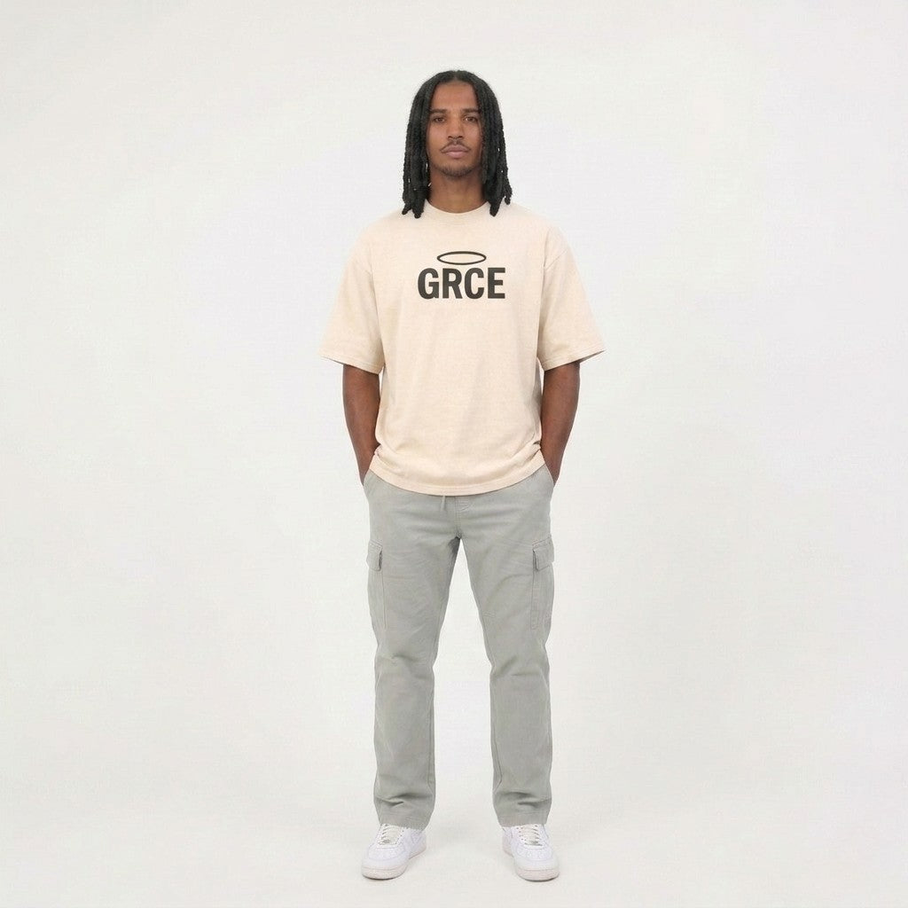 Person wearing a cream t-shirt with 'GRCE' logo and gray pants on a white background