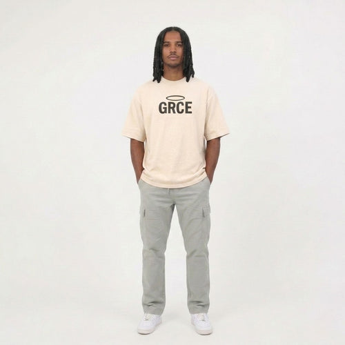 Person wearing a cream t-shirt with 'GRCE' logo and gray pants on a white background