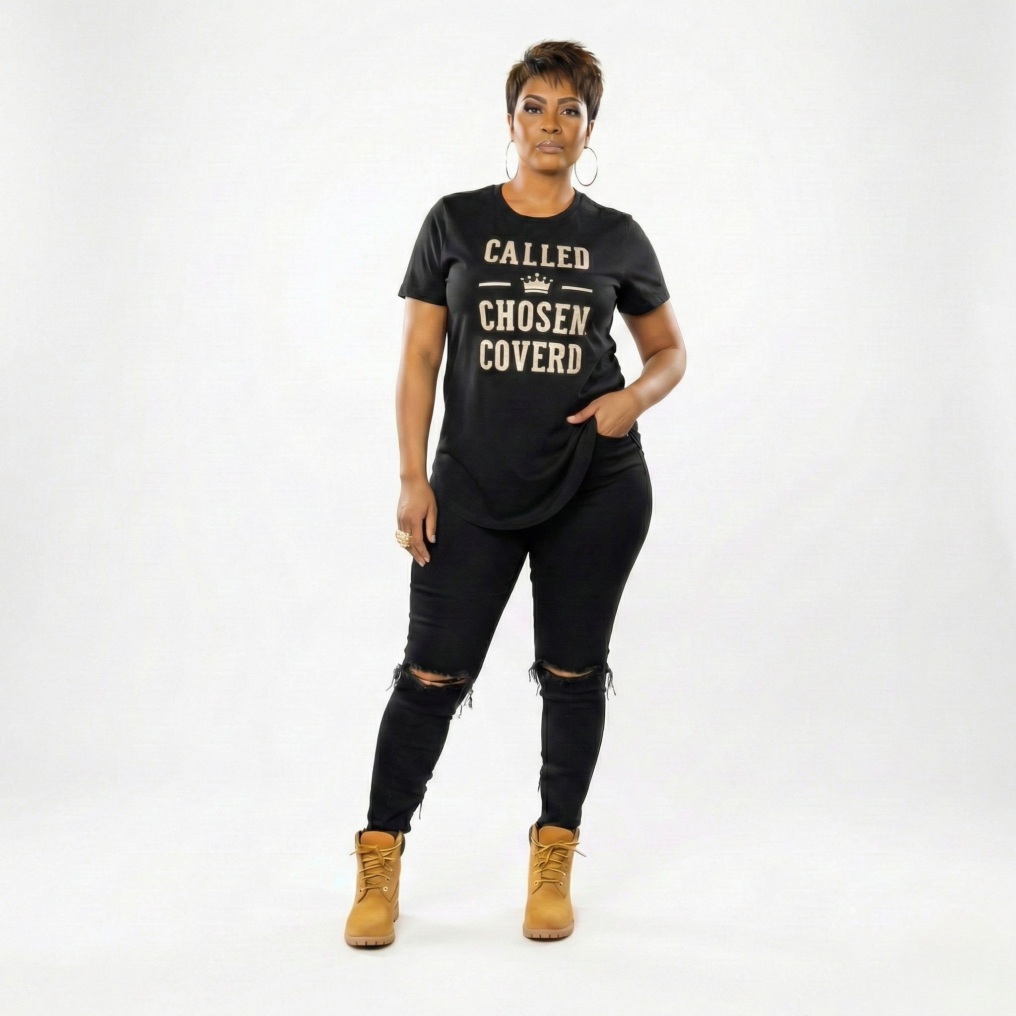Woman wearing a black t-shirt with text, black pants, and tan boots on a white background