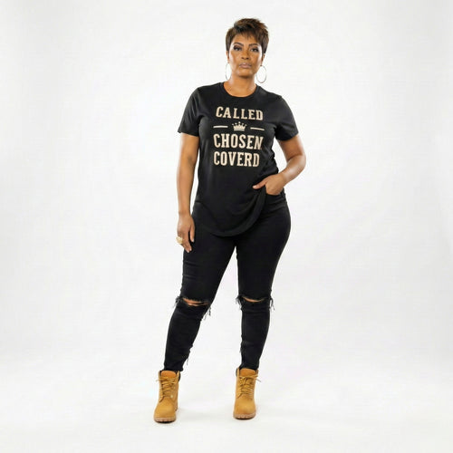 Woman wearing a black t-shirt with text, black pants, and tan boots on a white background