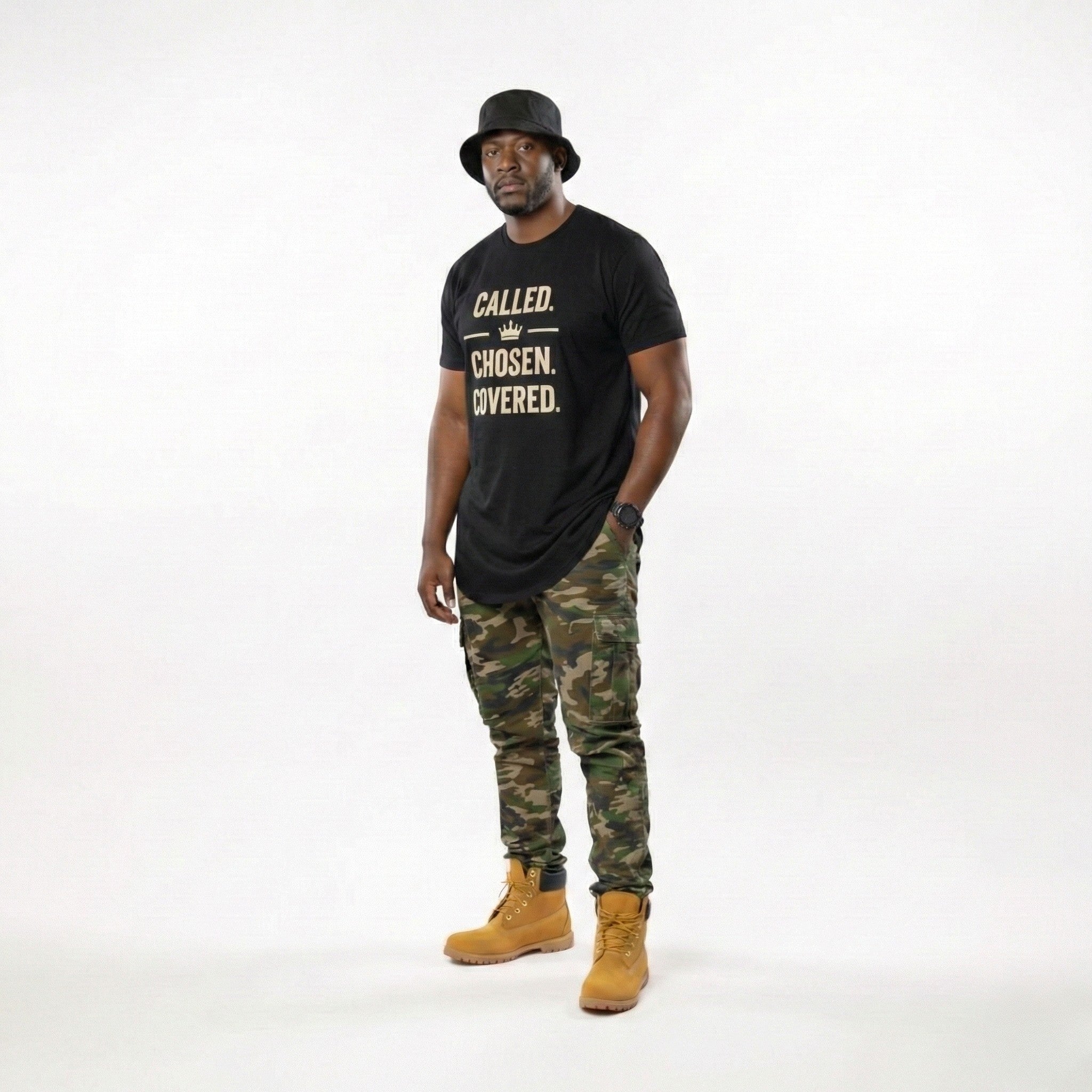 Man wearing a black t-shirt with text, camouflage pants, and yellow boots on a white background